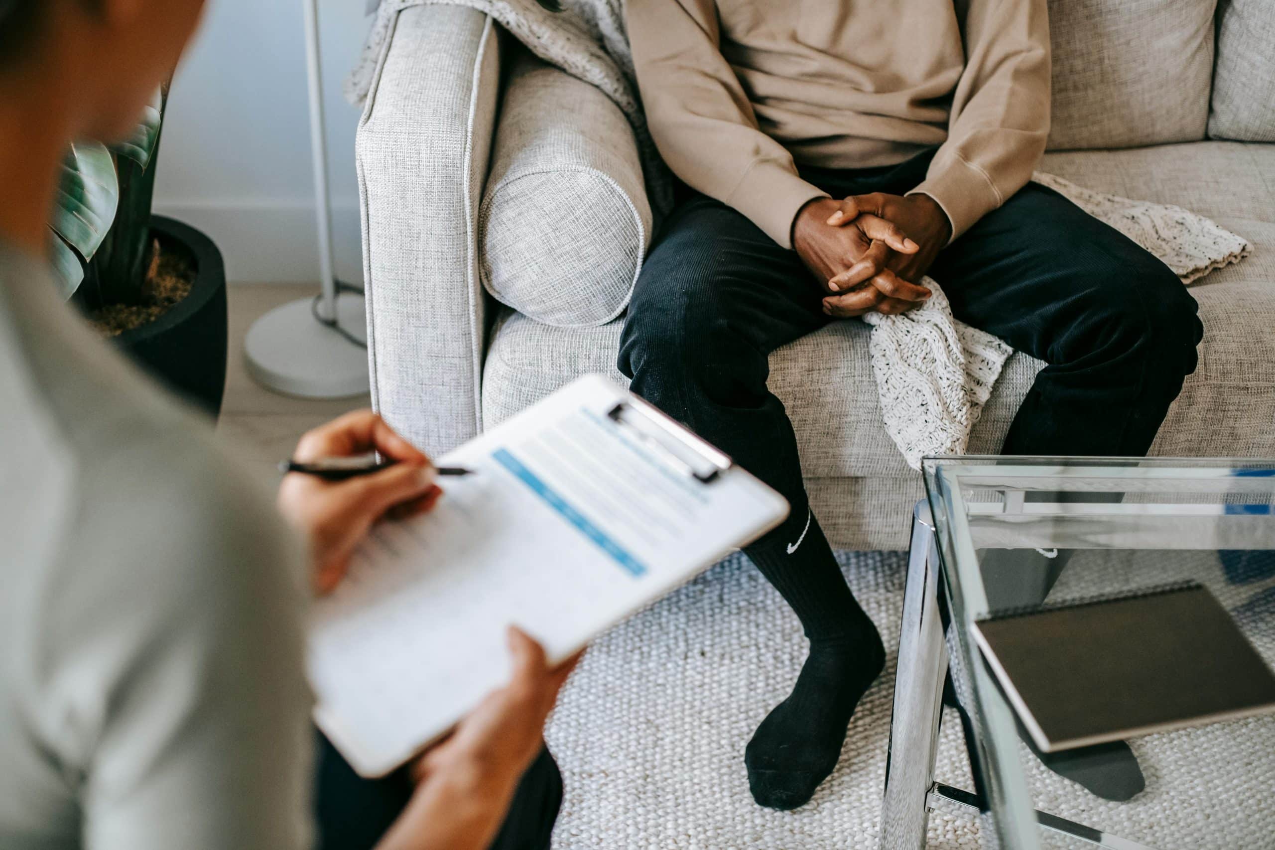 Man sitting in doctor's office while doctor holds clipboard.